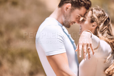Buy stock photo Female hand wearing engagement ring and romantic couple in love after outdoors marriage or proposal. Engaged woman, fiance or smiling, affectionate lovers hugging and embracing in background.