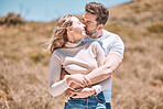 Hugging, embracing and in love young couple spending a romantic summer day in nature together. Happy partners on a getaway kissing, smiling and relaxing outdoors enjoying and loving the sunshine