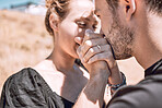 Engagement, loving and romantic man kissing woman's hand after proposing outside. Closeup of bonding couple holding and clasping hands while feeling happy or excited after girlfriend says yes to ring