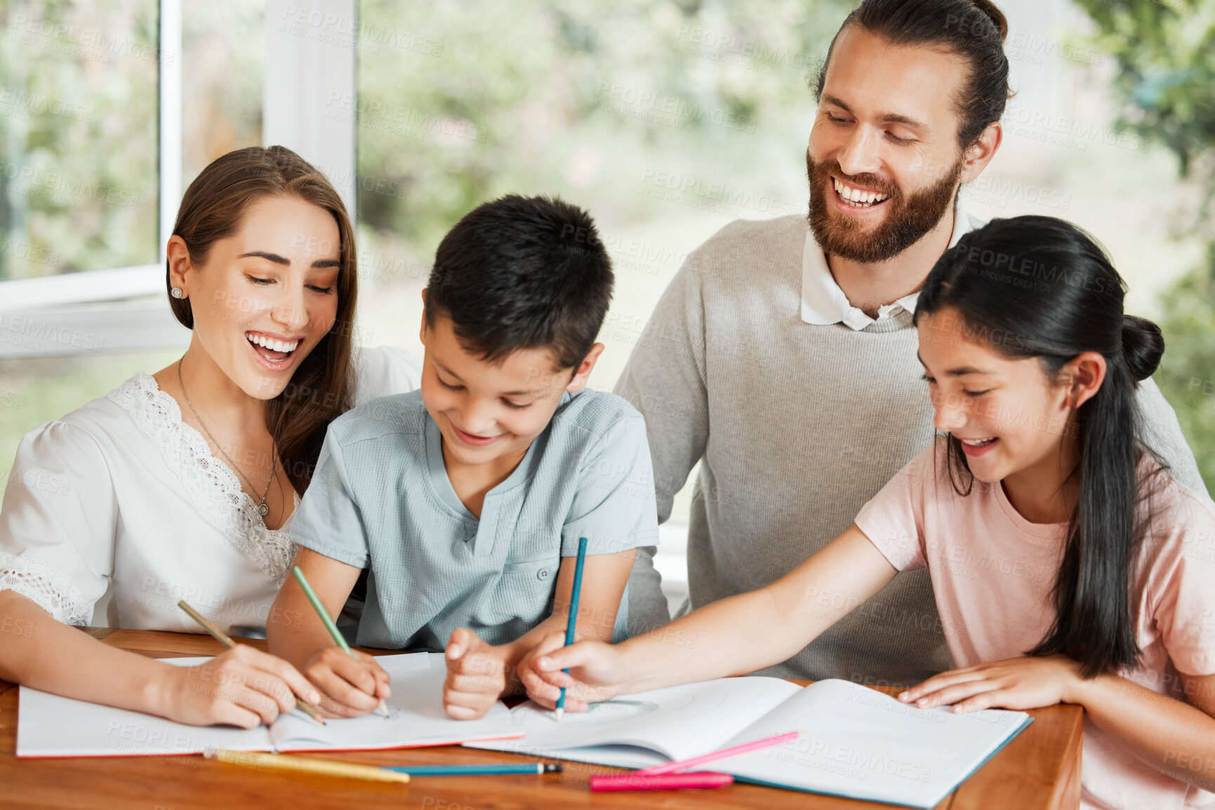 Buy stock photo Learning, education and homework with a family writing, drawing and studying together on a table at home. Parents and children bonding and spending time together while feeling happy and carefree