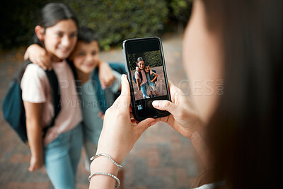 Buy stock photo Children first day of school and mother taking photos with a phone of her cute kids. Closeup of screen picture of brother and sister embracing while posing for their mom outside in the morning