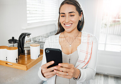 Buy stock photo Woman browsing, texting and reading on a phone in her kitchen at home. Smiling woman on social media online app, networking and messaging contacts while smiling at a funny post, meme or videos