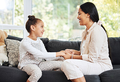 Buy stock photo Happy, smiling and talking mother and daughter bonding, holding hands and showing affection while relaxing on the couch together at home. Parent giving advice, support and care to a little girl