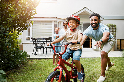 Buy stock photo Learning, bicycle and proud dad teaching his young son to ride while wearing a helmet for safety in their family home garden. Active father helping and supporting his child while cycling outside
