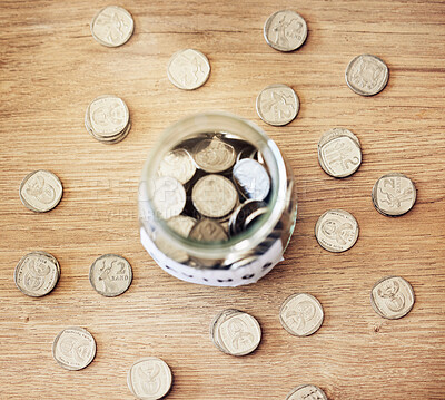 Buy stock photo Savings, investment and a jar full of coins on a wooden table for future financial growth or insurance. Overhead view of an overflowing container with money for a donation or retirement fund