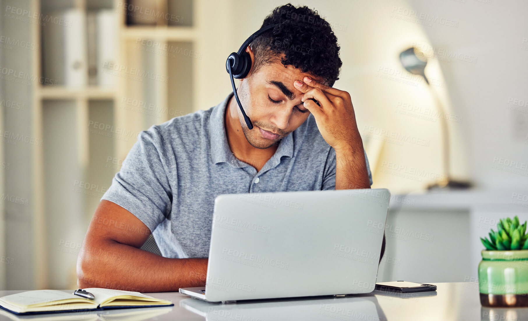 Buy stock photo Stressed, tired and frustrated call center agent feeling sick or ill in the office while working on his laptop. A worried and unhappy young telemarketing employee suffering from a headache and pain