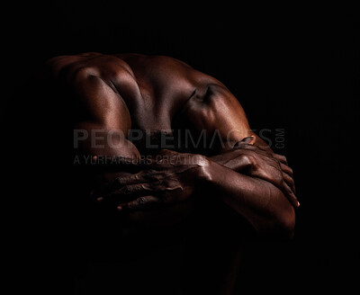 Buy stock photo Art, masculinity and artistic shadows with african man posing naked in studio isolated against a dark background. Muscular, macho and  artwork of a strong black man curled up with hands over his head