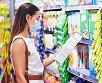 Customer, shopper and consumer reading label for nutritional ingredients on products, stock and groceries while shopping in supermarket store in covid pandemic. Woman deciding choice to buying food