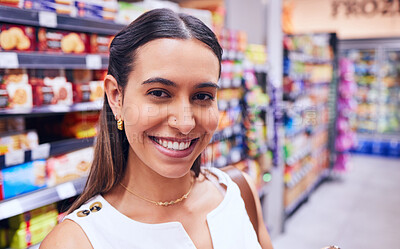 Buy stock photo Shopping, groceries and consumerism with a young woman in a grocery store, retail shop or supermarket aisle. Closeup portrait of a female standing with packed shelves of consumables in the background