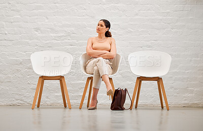 Buy stock photo Employment, hiring and recruitment with a young business woman sitting on a chair waiting for her interview with human resources. Female shortlist candidate looking impatient or nervous for a meeting