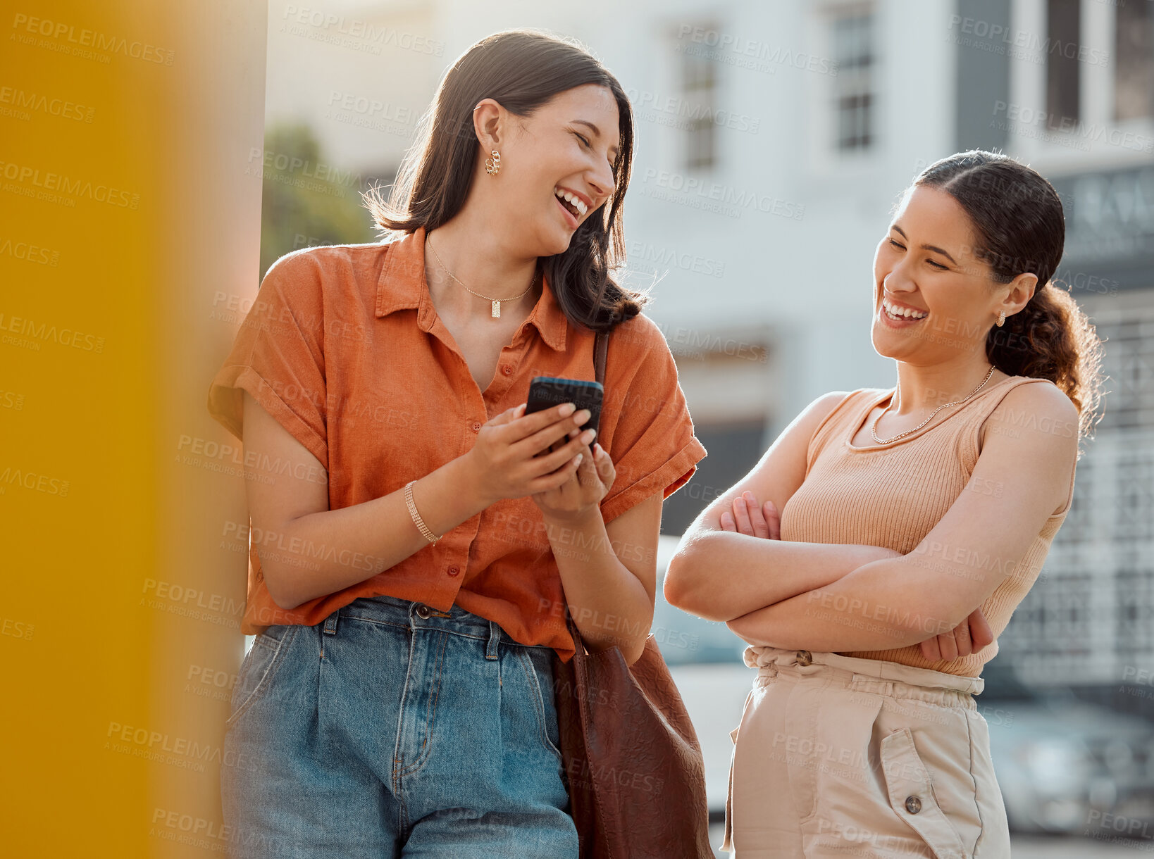 Buy stock photo Happy women, friends talking, having fun and laughing while reading a text on a phone together outside. Young, carefree and relaxed females chatting, enjoying a conversation and free time downtown