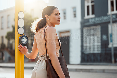 Buy stock photo Attractive female pedestrian ready to cross the street, waiting for green light and pressing the button at a crossing Young city woman on a morning walk to work, standing and looking out for traffic.