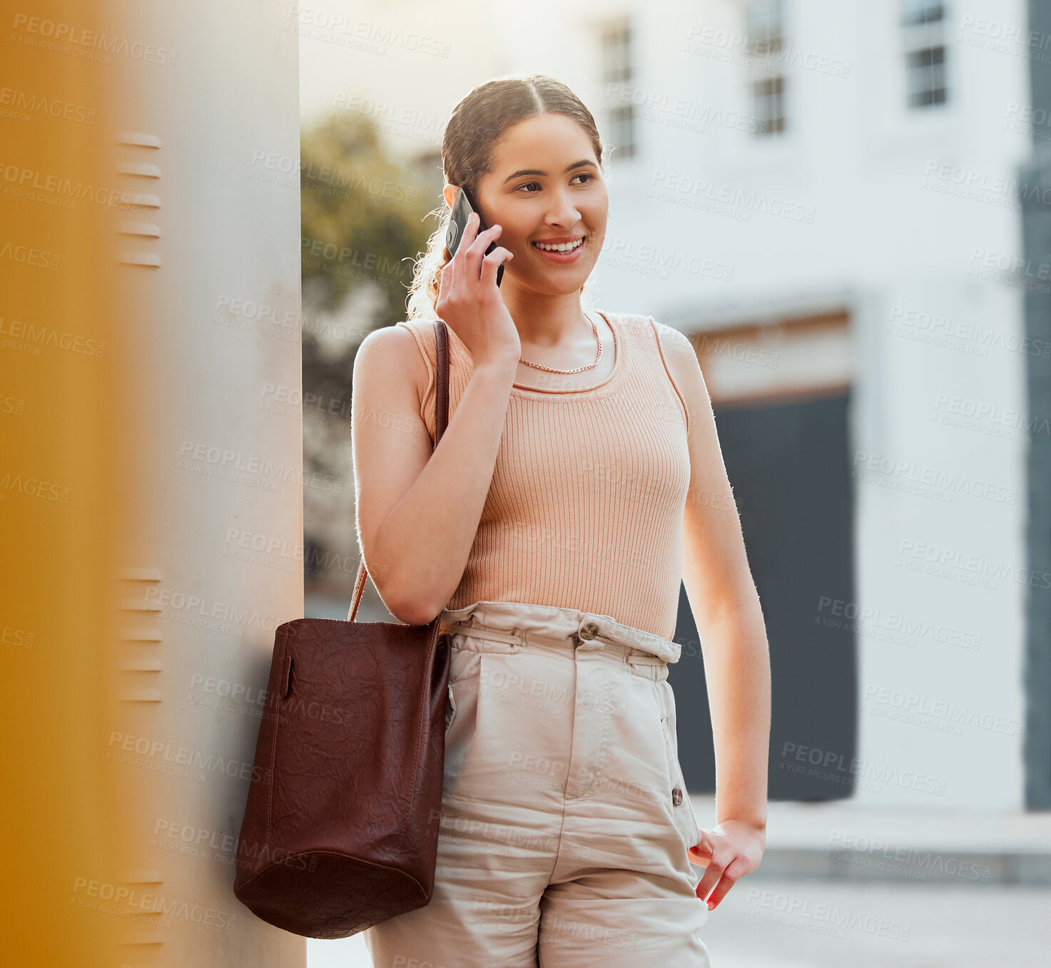 Buy stock photo Casual woman talking on phone call, networking and making conversation while standing in the urban city alone. Trendy, smiling and cheerful female commuting and traveling to work in the morning