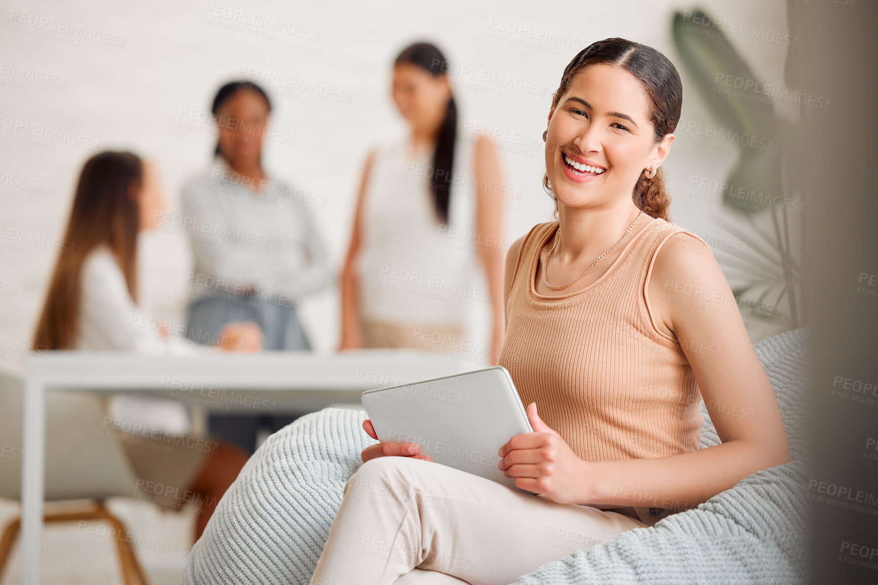 Buy stock photo Trendy designer relaxing on beanbag chair while smiling, laughing and working on digital tablet in a creative startup agency. Portrait of a cool, comfortable and happy business woman browsing online