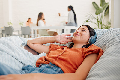 Buy stock photo Relaxing, carefree and listening to music with a young business woman thinking, resting and lying in an office during break. Enjoying the comfort of a beanbag chair and working as a creative designer
