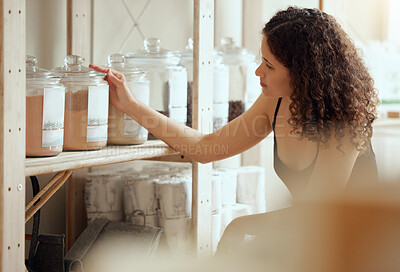 Buy stock photo Zero waste shopping or choosing organic and vegan products or spices on a shelf of a shop. A young woman customer or consumer buying condiments in jars at a food store on a weekend