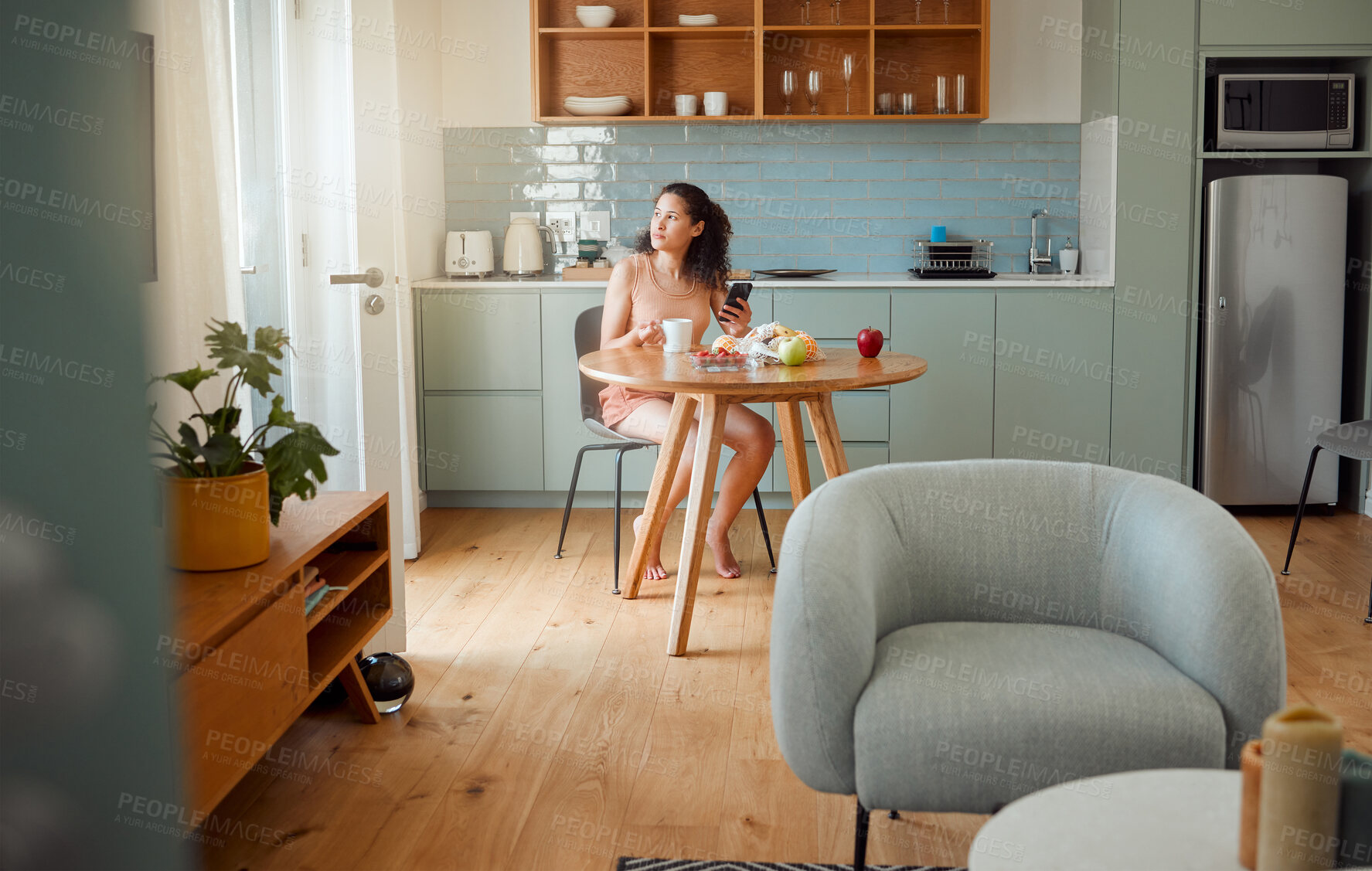 Buy stock photo Woman on phone thinking of breakfast idea, healthy snack while drinking coffee in the morning in stylish kitchen. Relaxed and alone girl looking nostalgic in a modern apartment with interior design