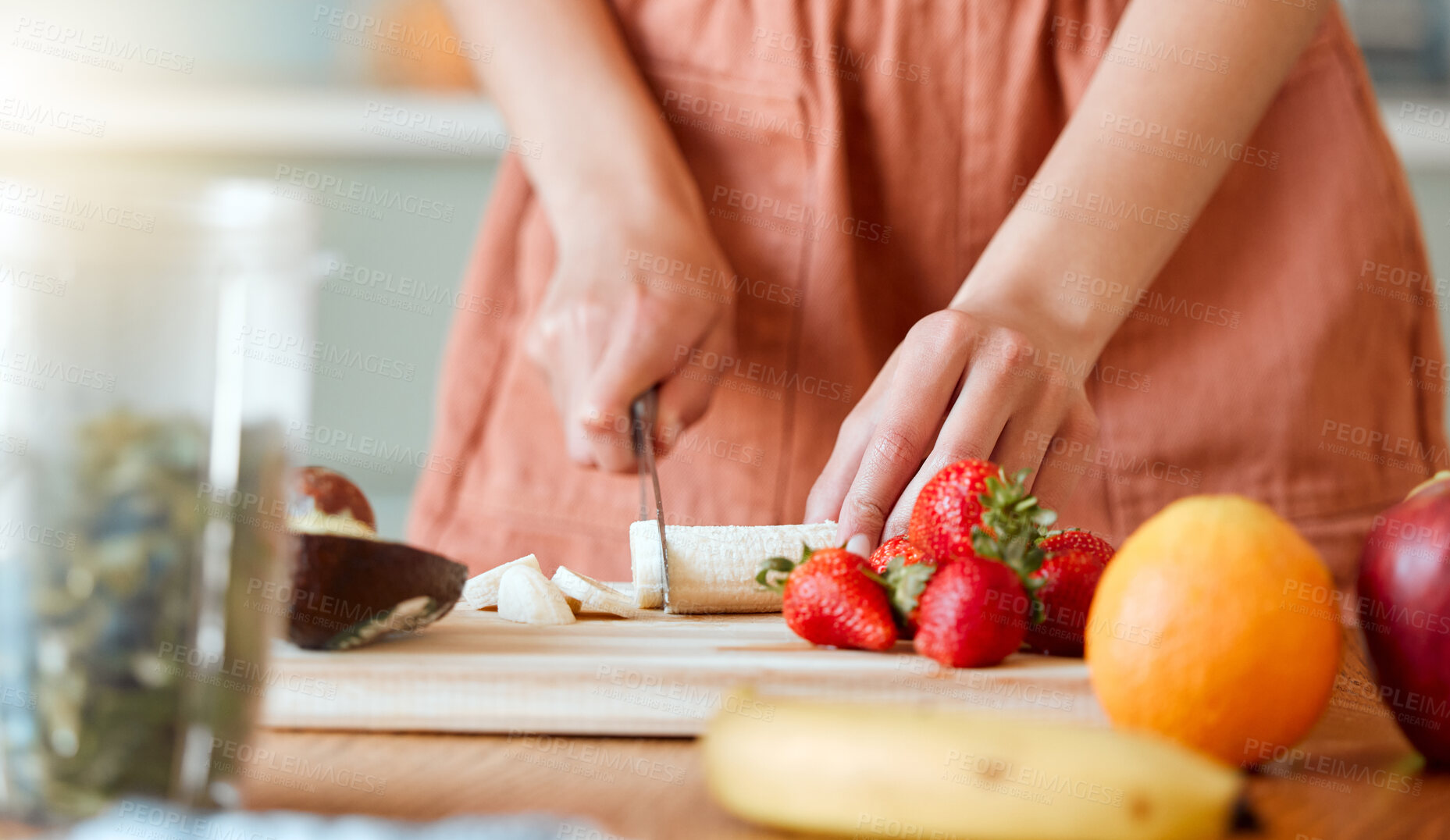 Buy stock photo Healthy woman cutting fruit to make a smoothie with nutrition for an organic diet at home. Closeup of caucasian female hands chopping fresh produce for a health drink in a kitchen. 