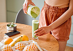 Closeup of a young female pouring green healthy smoothie to detox, drinking vitamins and nutrients. Woman having a fresh fruit juice to cleanse and provide energy for gym session.
