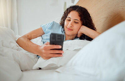 Buy stock photo Woman texting, checking messages and holding phone while reading sms and lying awake in her bed in the morning. Happy, content and smiling female playing a game, browsing the internet or social media