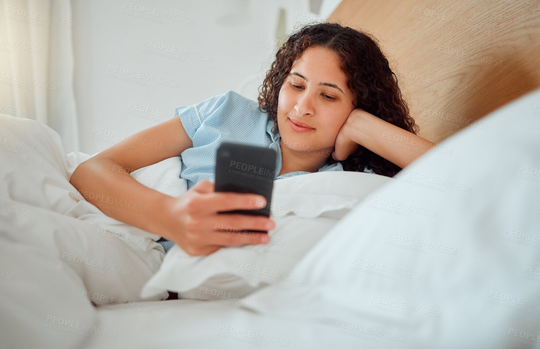 Buy stock photo Woman texting, checking messages and holding phone while reading sms and lying awake in her bed in the morning. Happy, content and smiling female playing a game, browsing the internet or social media
