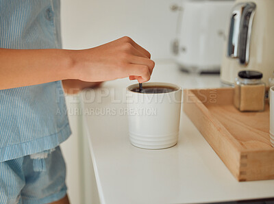 Buy stock photo Making fresh, hot morning coffee indoors on a kitchen counter to start the day. Hand closeup of preparing a warm beverage and drink inside with a female standing in pajamas at home