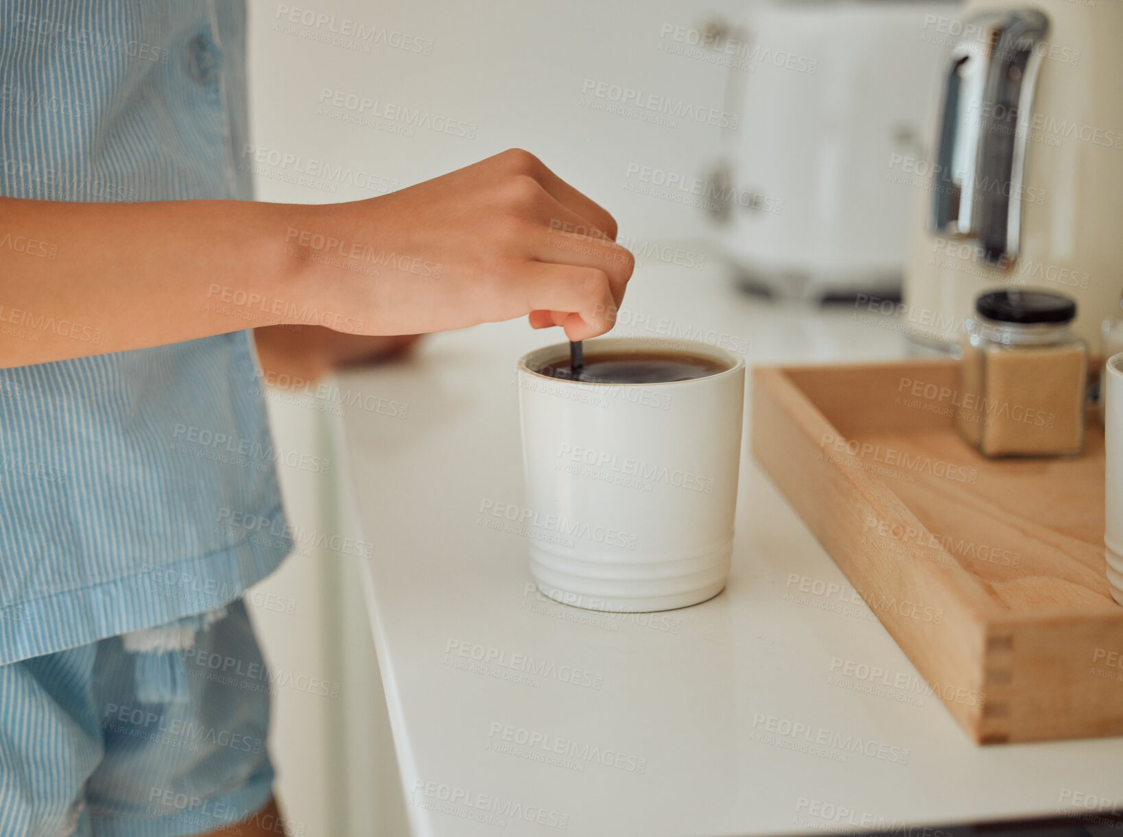 Buy stock photo Making fresh, hot morning coffee indoors on a kitchen counter to start the day. Hand closeup of preparing a warm beverage and drink inside with a female standing in pajamas at home