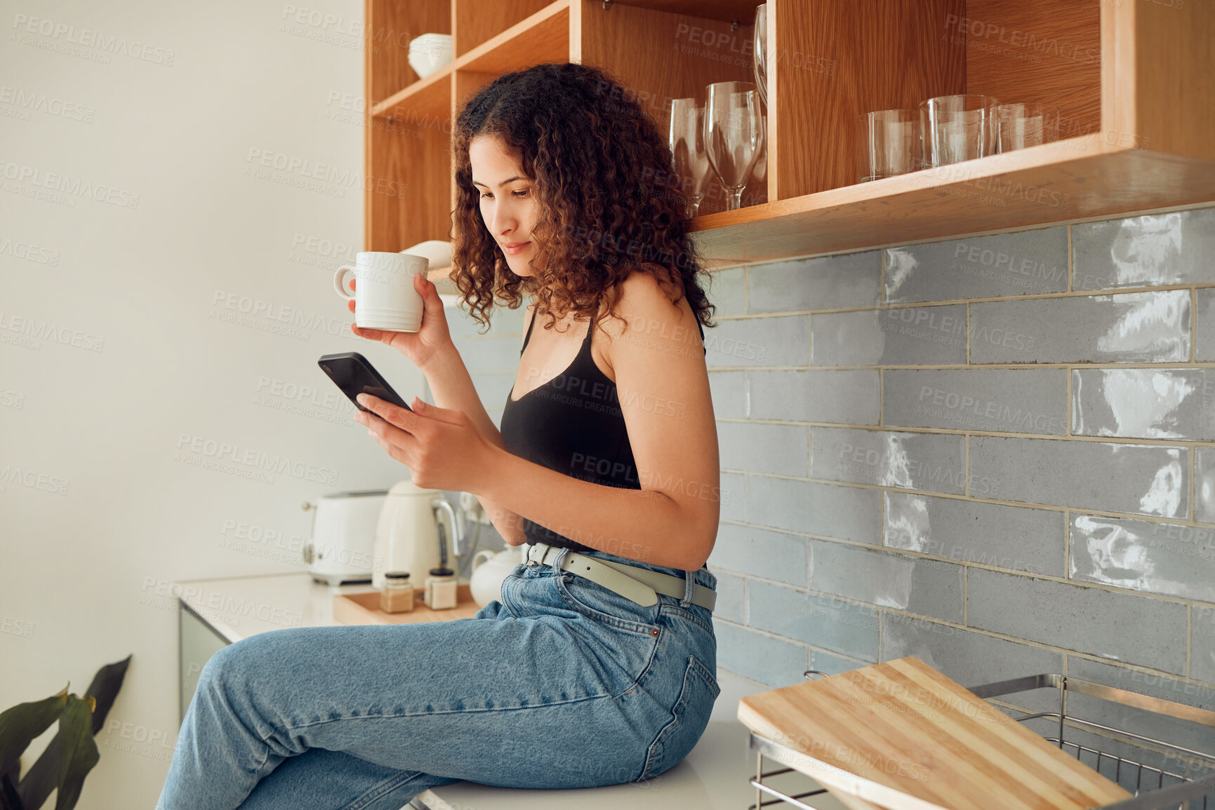 Buy stock photo Woman texting, chatting on the phone while relaxed, carefree and sitting on kitchen counter. Young, relaxing and casual female student at home looking at social media, pictures or videos