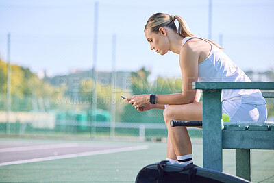 Buy stock photo Fit tennis player with phone checking fitness goal progress on a sports exercise app online while taking a break at the court. A sportswoman checking messages on cellphone and waiting for a coach