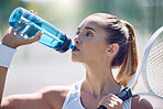 Attractive female tennis player on a water break, drinking from a plastic bottle during a match. A beautiful young lady playing the sport and hydration game to stay fit for a healthy happy lifestyle.