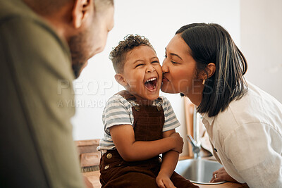 Buy stock photo Happy boy getting a kiss by caring mother, bonding and laughing during family time at home. Young parents sharing a sweet moment of parenthood with their playful child, relaxing and carefree together