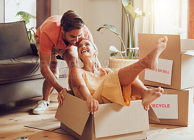 Buy stock photo Property, buying and fun couple moving into a new house together, being playful, bonding and unpacking. Happy young husband and wife playing with boxes, laughing and having fun being silly at home