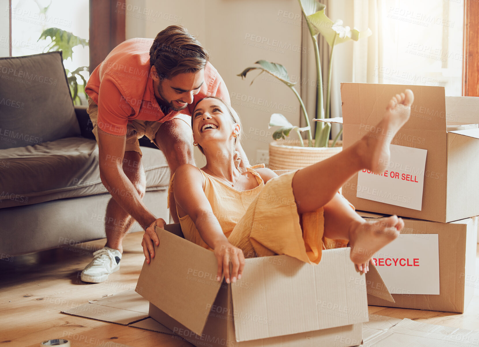 Buy stock photo Property, buying and fun couple moving into a new house together, being playful, bonding and unpacking. Happy young husband and wife playing with boxes, laughing and having fun being silly at home