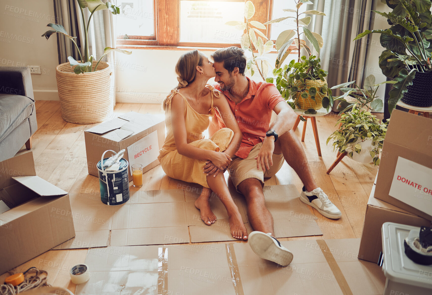 Buy stock photo New home owners moving into a house showing affectionate, taking a break from painting and remodeling the living room interior design. In love and loving house wife kissing husband after decorating 