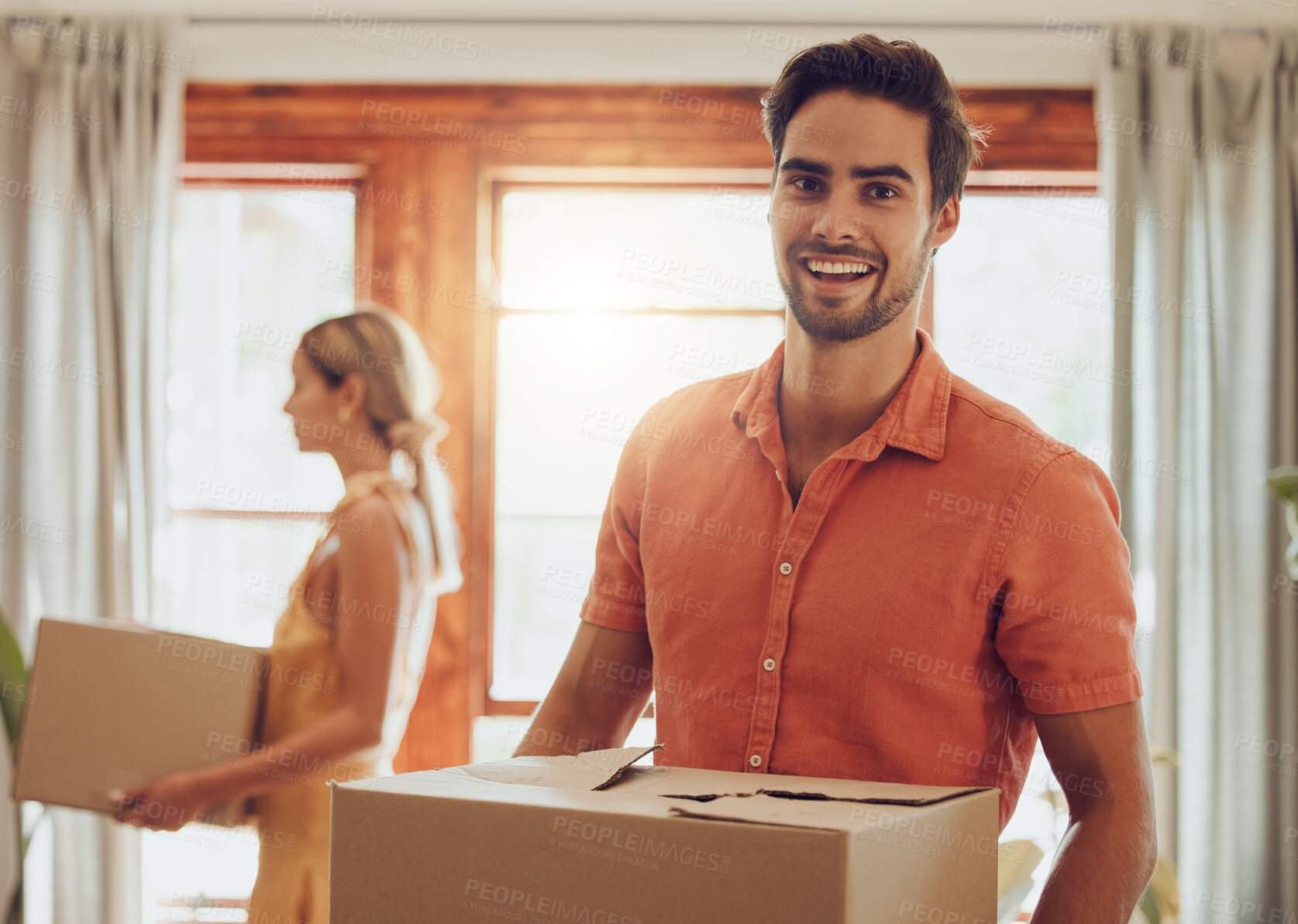 Buy stock photo Happy couple moving into new home, people carrying boxes to property and relocating to apartment together. Portrait of smiling, cheerful and handsome man packing for move with woman standing at house