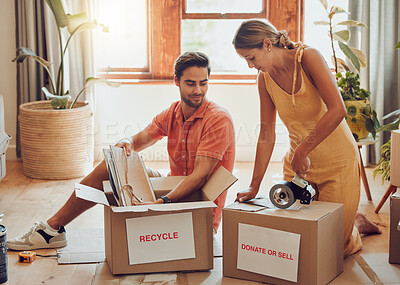 Buy stock photo Donate, packing and boxes of a young couple working together to pack equipment at home. Relationship, togetherness and teamwork of a man and woman organizing their house for recycling