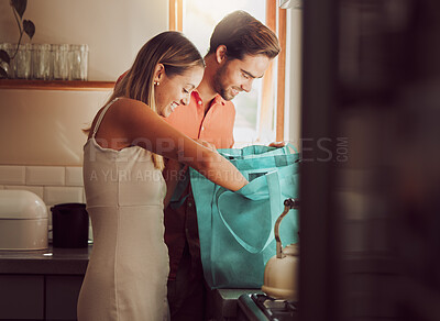 Buy stock photo Couple home after grocery shopping at supermarket store. Retail consumer, sustainable shopper and young people unpacking and checking food products, goods and groceries from reusable bag in a kitchen