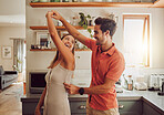 Joyful, dancing and loving couple bonding and having fun in the kitchen together at home. Energetic, fun and active relationship sharing a dance and romantic moment while enjoying their anniversary.