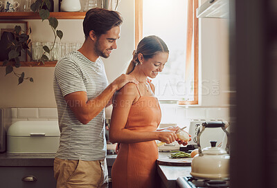 Buy stock photo Romantic, caring and loving young couple supporting each other while preparing a meal in the kitchen. Man and woman in a happy, stressless and relaxed relationship together cooking at home. 