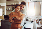 Love, romance and fun with a couple embracing, laughing in a kitchen and sharing an intimate moment. Romantic boyfriend and girlfriend hugging, enjoying their relationship and being carefree together