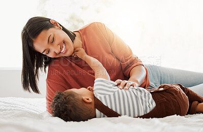 Buy stock photo Happy, love and family time with a mother and son being playful and bonding on a bed at home. Parent playing with her child, smiling and enjoying motherhood. Single mom embracing her son.