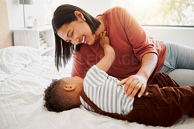 Buy stock photo Happy, loving family with a mother and son being playful and bonding on a bed at home. Smiling parent playing with her child, laughing and enjoying motherhood. Single parent embracing her son