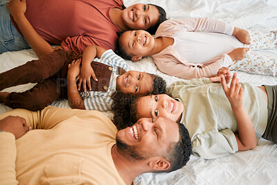 Buy stock photo Happy mother, father and children together as a family lying, relaxing and bonding in the bedroom at home. Mom, dad and kids smiling, free and loving quality time together. Siblings with parents
