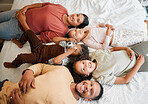 Fun family, children and parents bonding while lying on a bed in home bedroom from above. Portrait of playful, smiling and happy kids having fun with mother and father on weekend and making memories