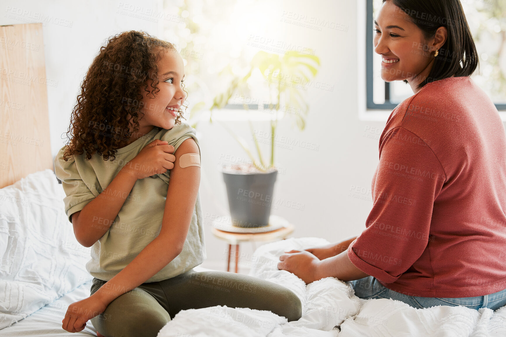 Buy stock photo Girl with covid vaccine shows mother vaccinated arm with plaster as covid19 protection for a kid in a bedroom home. Child after getting an injection bonding with her mom in the bedroom