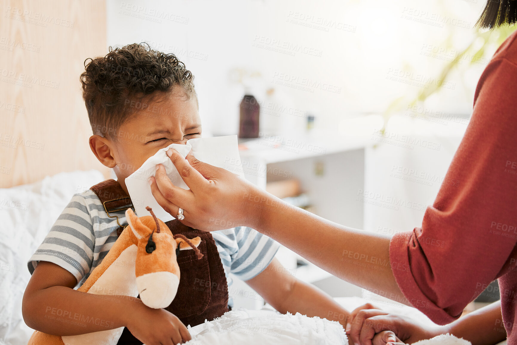 Buy stock photo Flu, sick or cold child with parent sneezing, blowing and wiping runny nose while ill with covid virus, sinus and allergy symptoms in bed at home. Mother caring for stuffy and congested little son