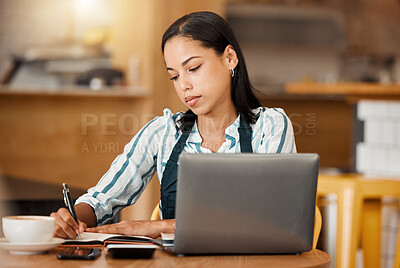 Buy stock photo Cafe owner, coffee shop manager or small business entrepreneur writing notes and working on a laptop in her startup. Young female looking serious while managing finance and capital of her bistro