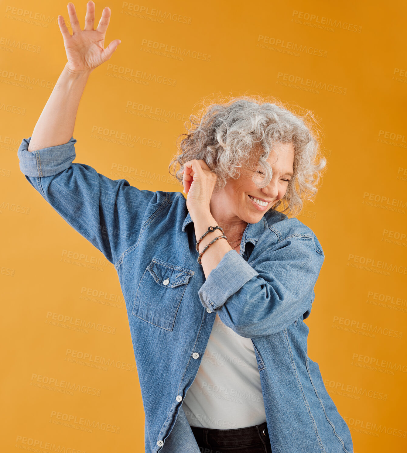 Buy stock photo Celebrating, partying and dancing mature woman, happy and cheerful senior making waving hand gesture and smiling. Elderly caucasian woman having fun while she dances against an orange background