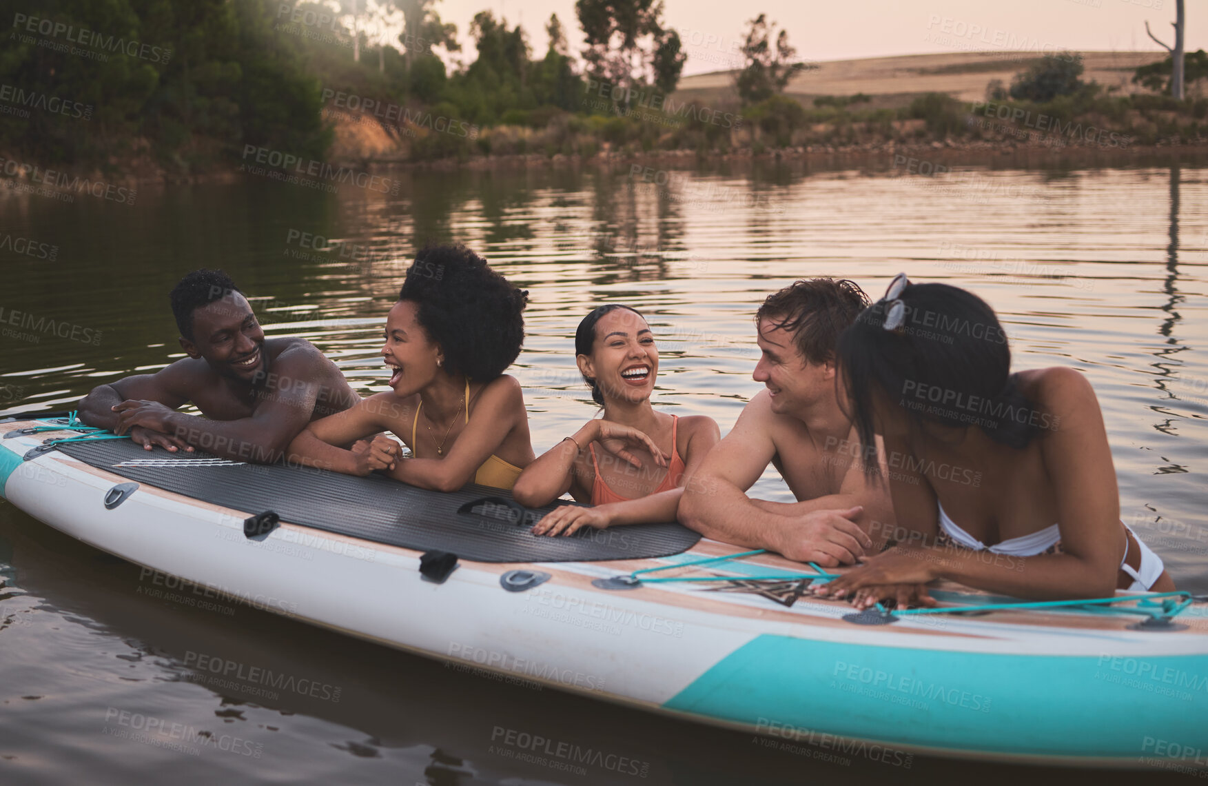 Buy stock photo Friends, vacation and having fun while leaning on a paddle board and talking in a lake. Happy and diverse people laughing while enjoying the water and friendship on their holiday and nature travel

