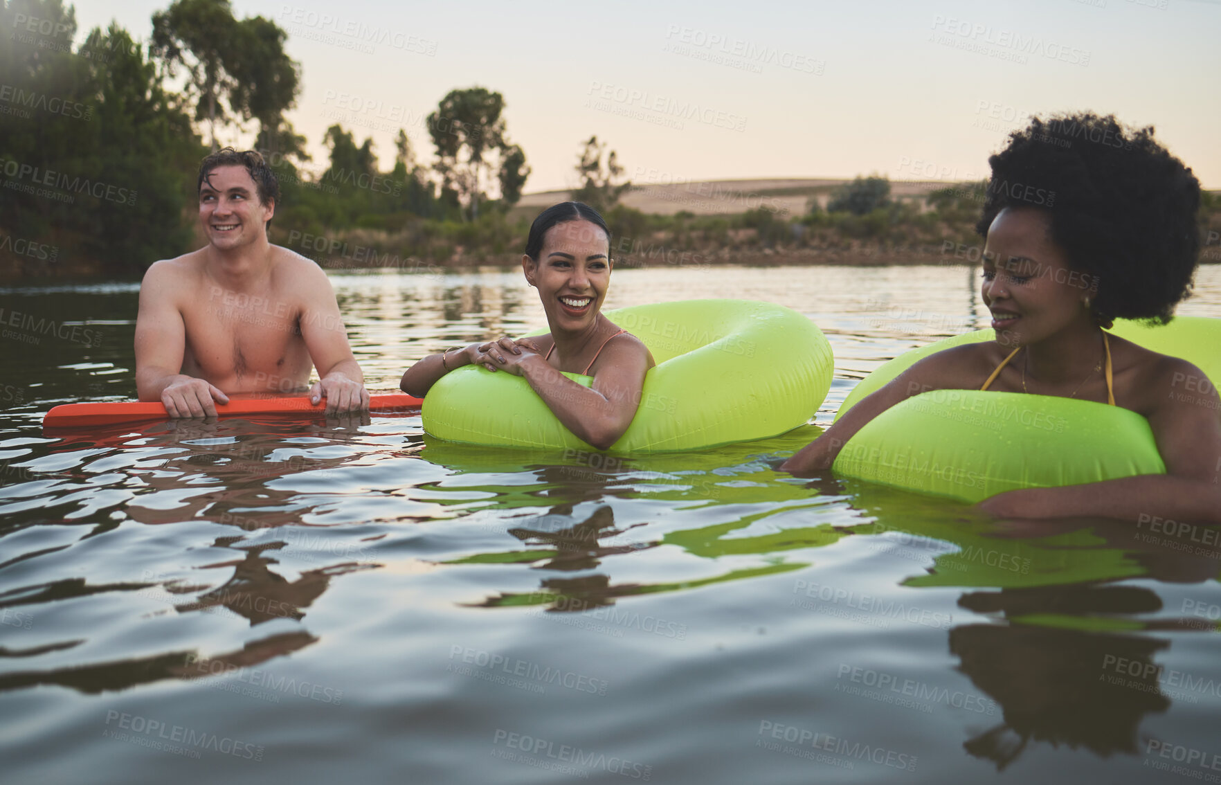 Buy stock photo Fun group of diverse friends relaxing in lake water, enjoying nature and bonding on a getaway vacation in the countryside together. Happy men and women laughing, smile and looking relaxed on holiday